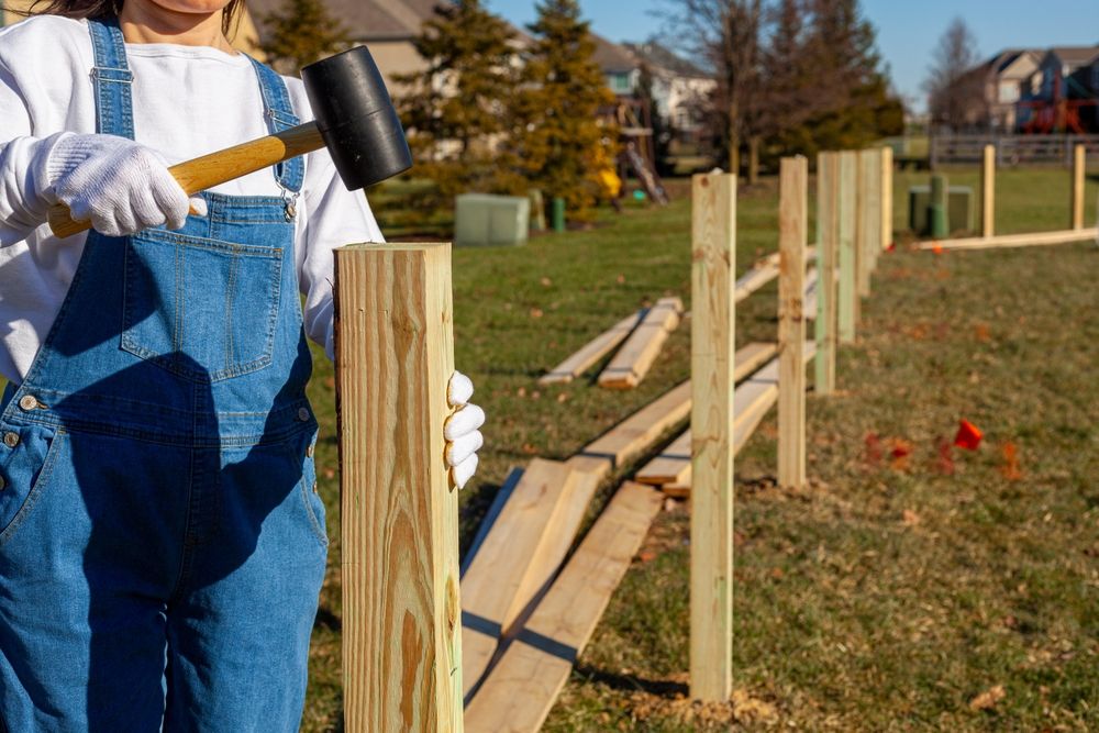 A woman in overalls installs a new fence